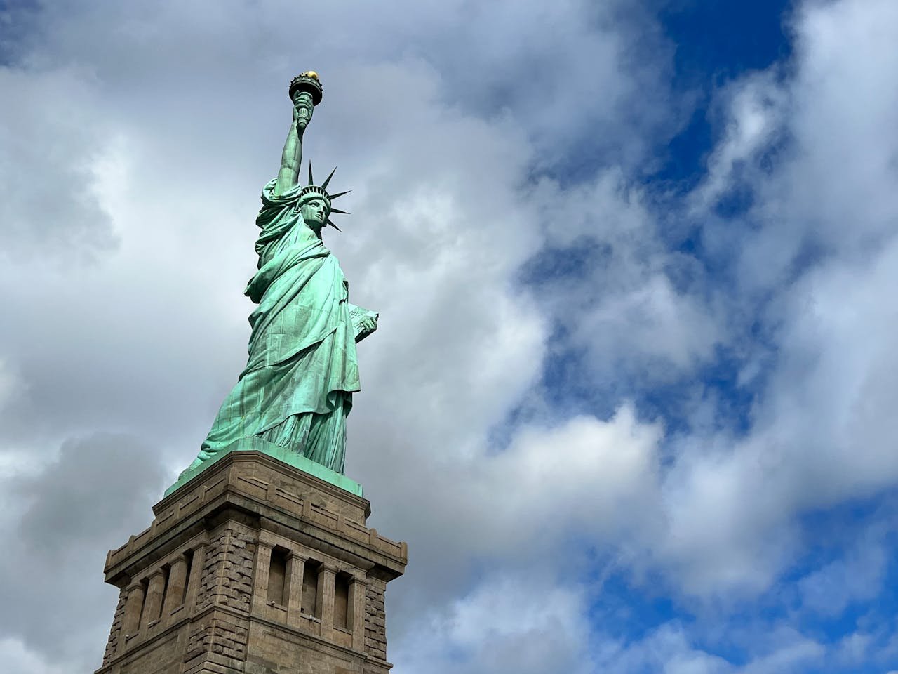 Iconic view of the Statue of Liberty under a partly cloudy sky, representing freedom.